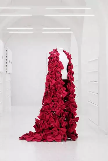 A mannequin bust draped with a coat made of red bows