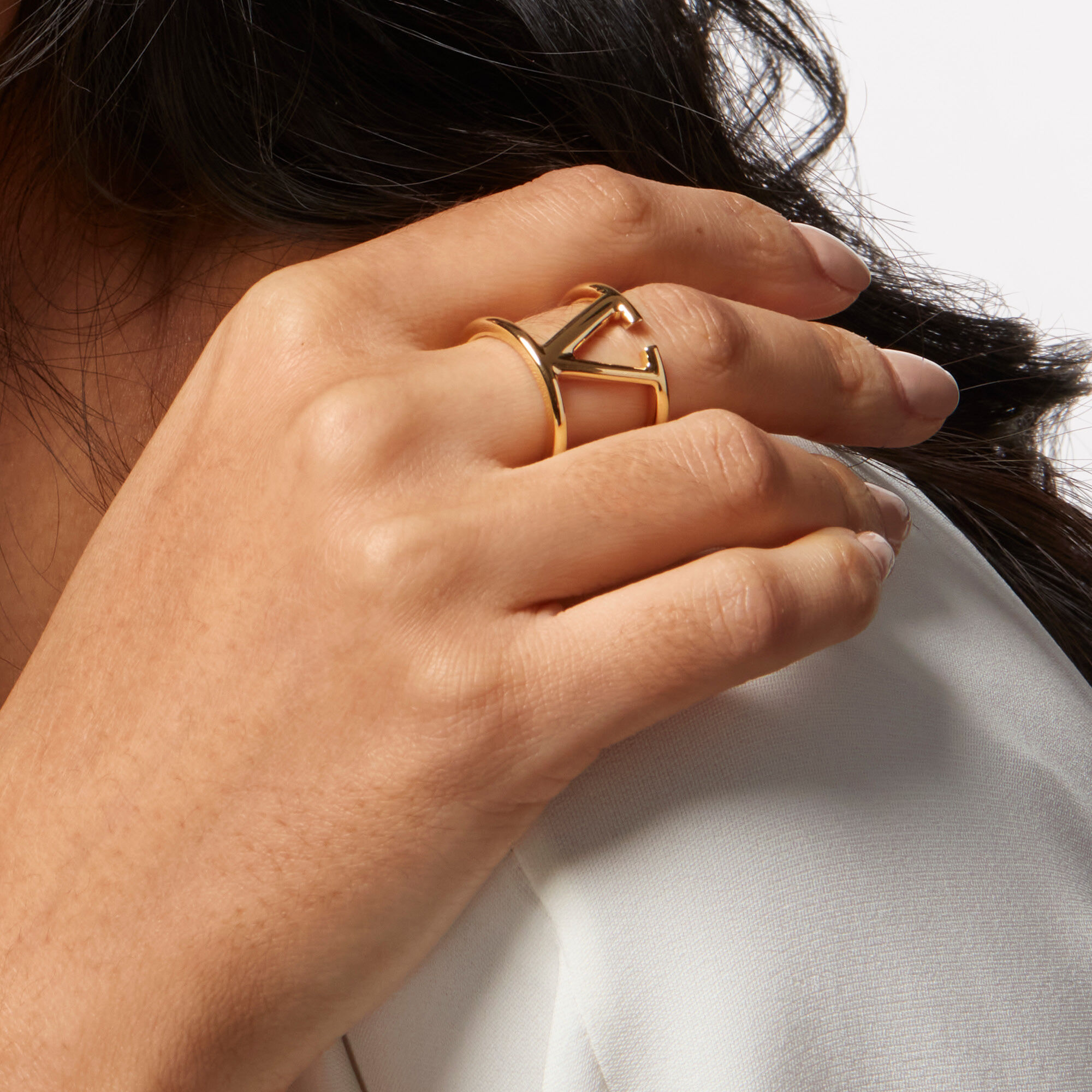 A woman resting her hand on her shoulder wearing a Valentino Beauty ring