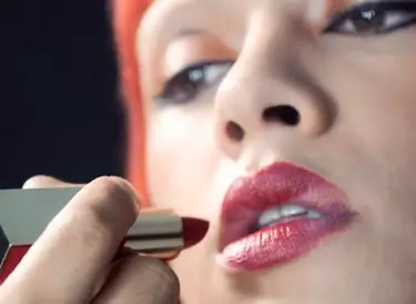 Makeup artist applying red lipstick to woman's lips