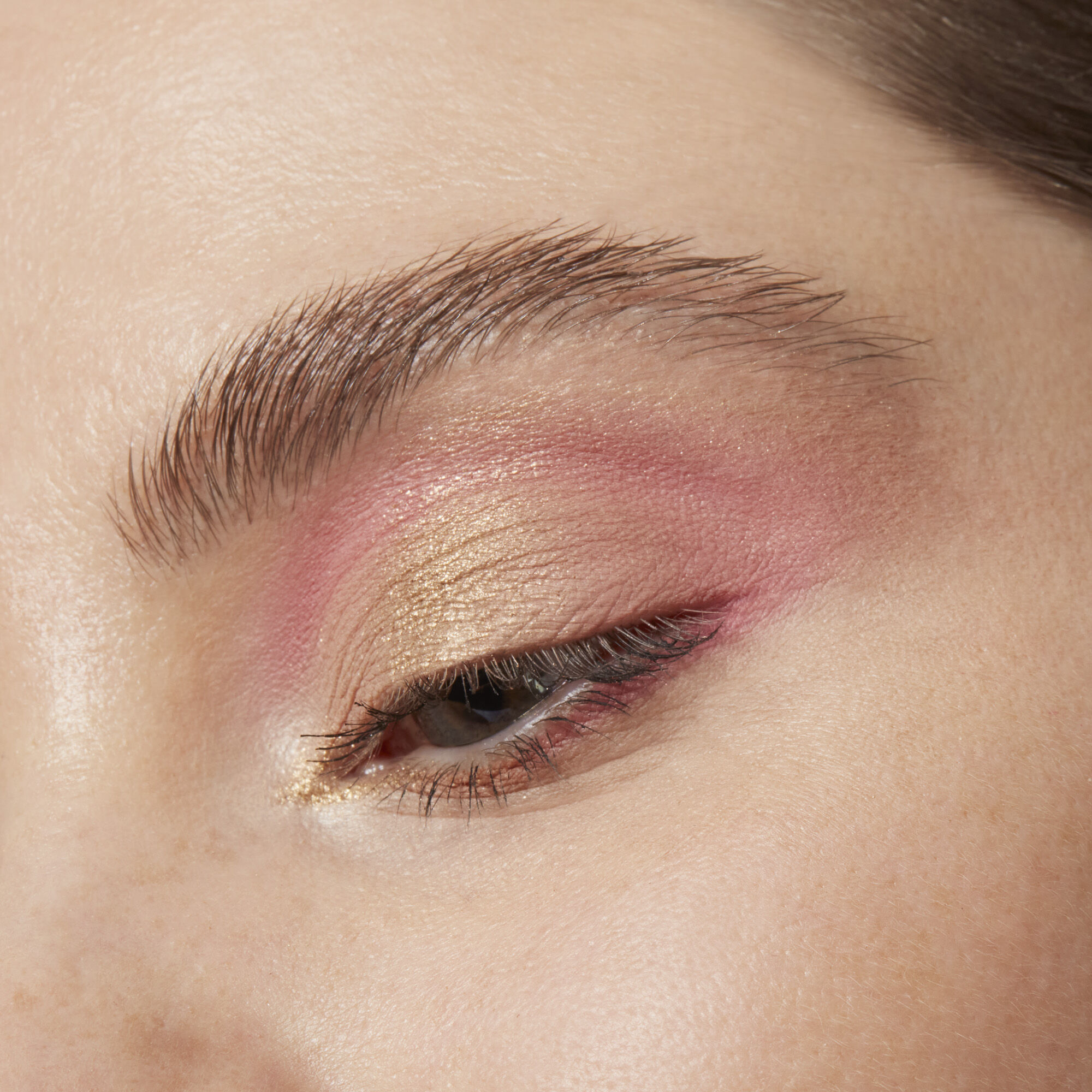 Close-up of an eye with pink and gold eye makeup