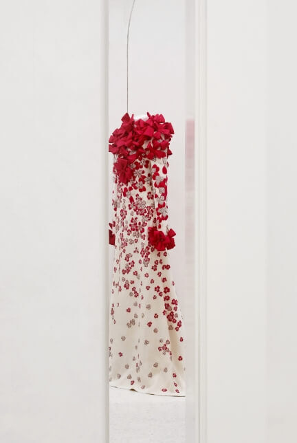Mirror reflection of mannequin draped with white and red bows and flowers 