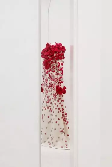 Mirror reflection of mannequin draped with white and red bows and flowers