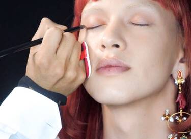 A makeup artist applying eye makeup to model