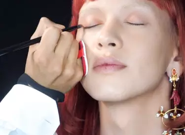 A makeup artist applying eye makeup to model