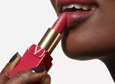 Close-up of a model applying lipstick to her lips