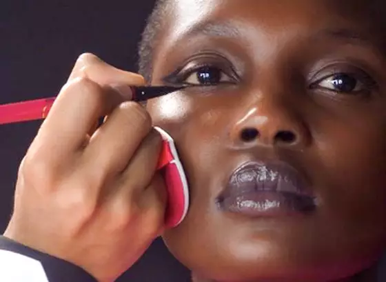 Makeup artists applying eyeliner to a model's lower lash line