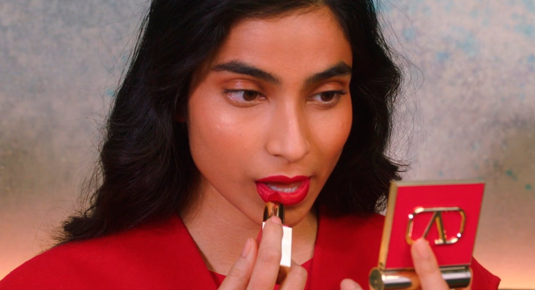 A woman applying Rosso Valentino Mini Lipstick